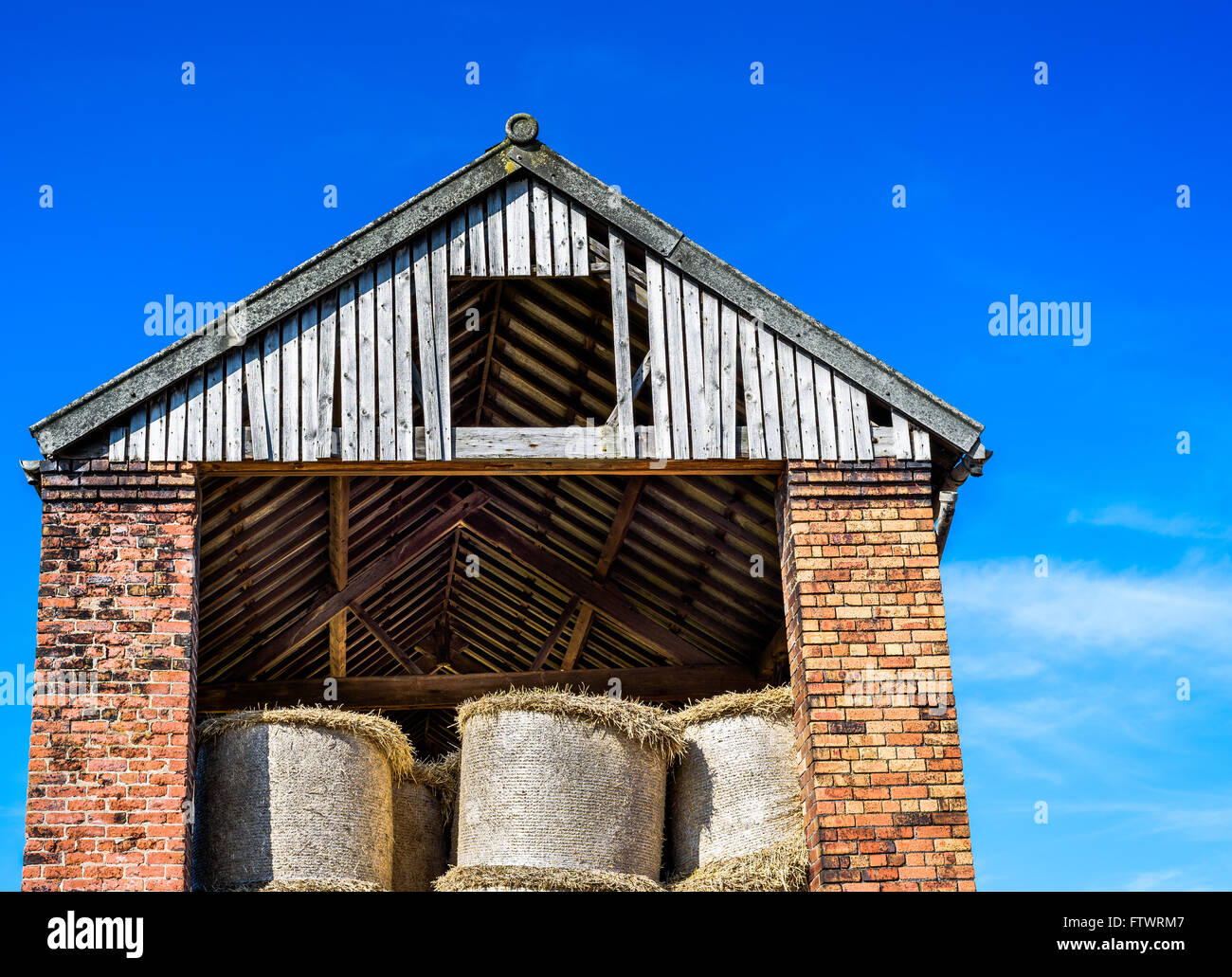 Ein Backstein und Holz Scheune mit einer Ernte von Heu. Stockfoto