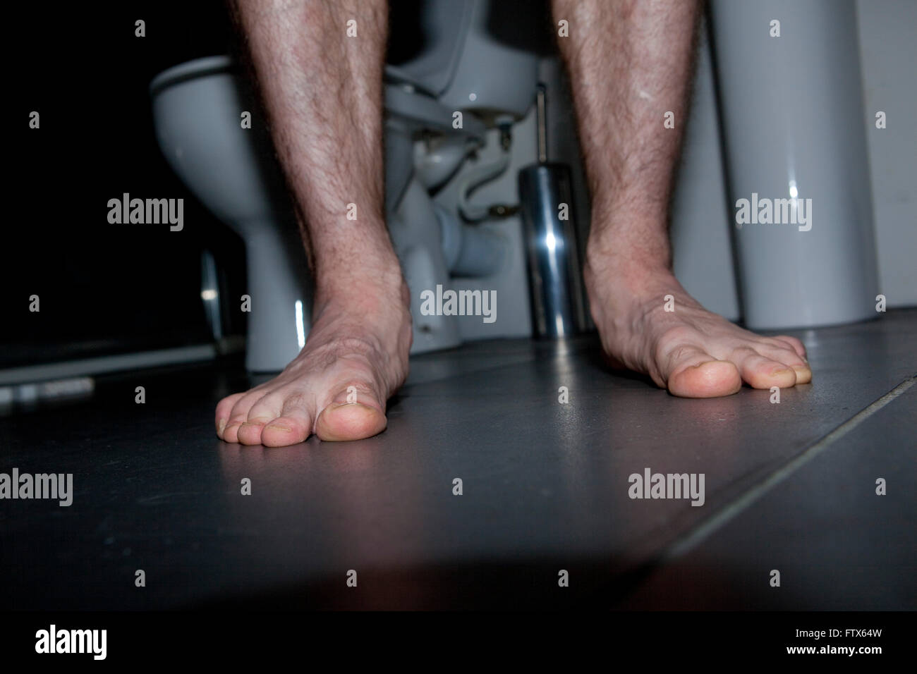 Ein altes mans behaarte Beine, die aus einem niedrigen Winkel gezeigt, während er in einem Bad, wc oder WC steht. Stockfoto