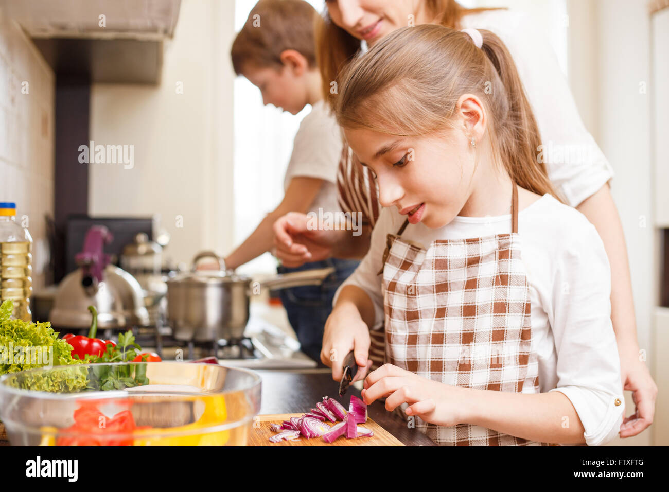 Familie kochen Hintergrund. Mama und Tochter schneiden Zwiebel Salat in der Küche Stockfoto