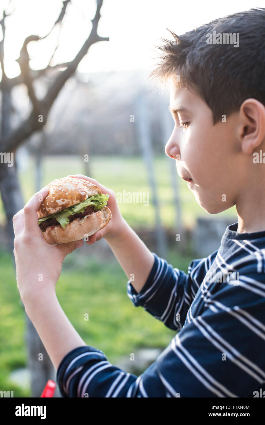 Junge im Garten hält einen hamburger Stockfoto
