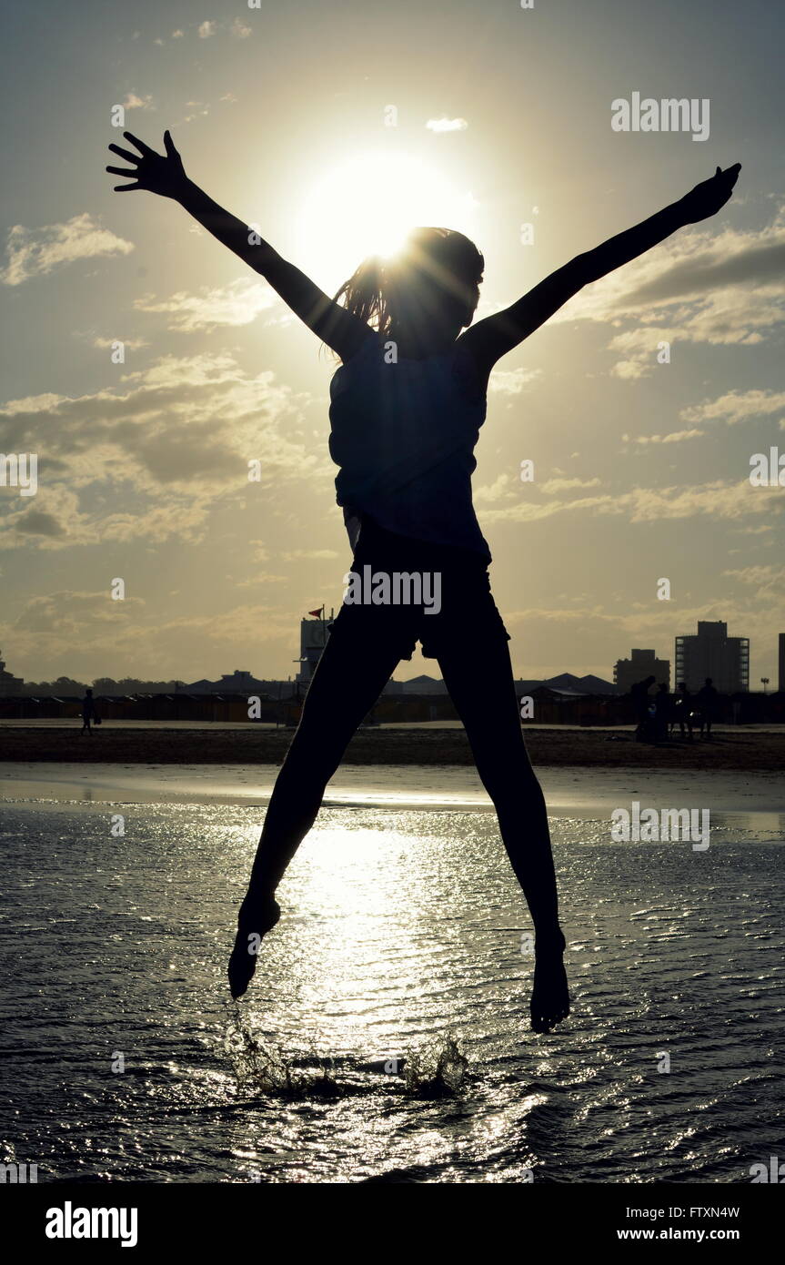 Silhouette eines Mädchens am Strand in die Luft springen Stockfoto
