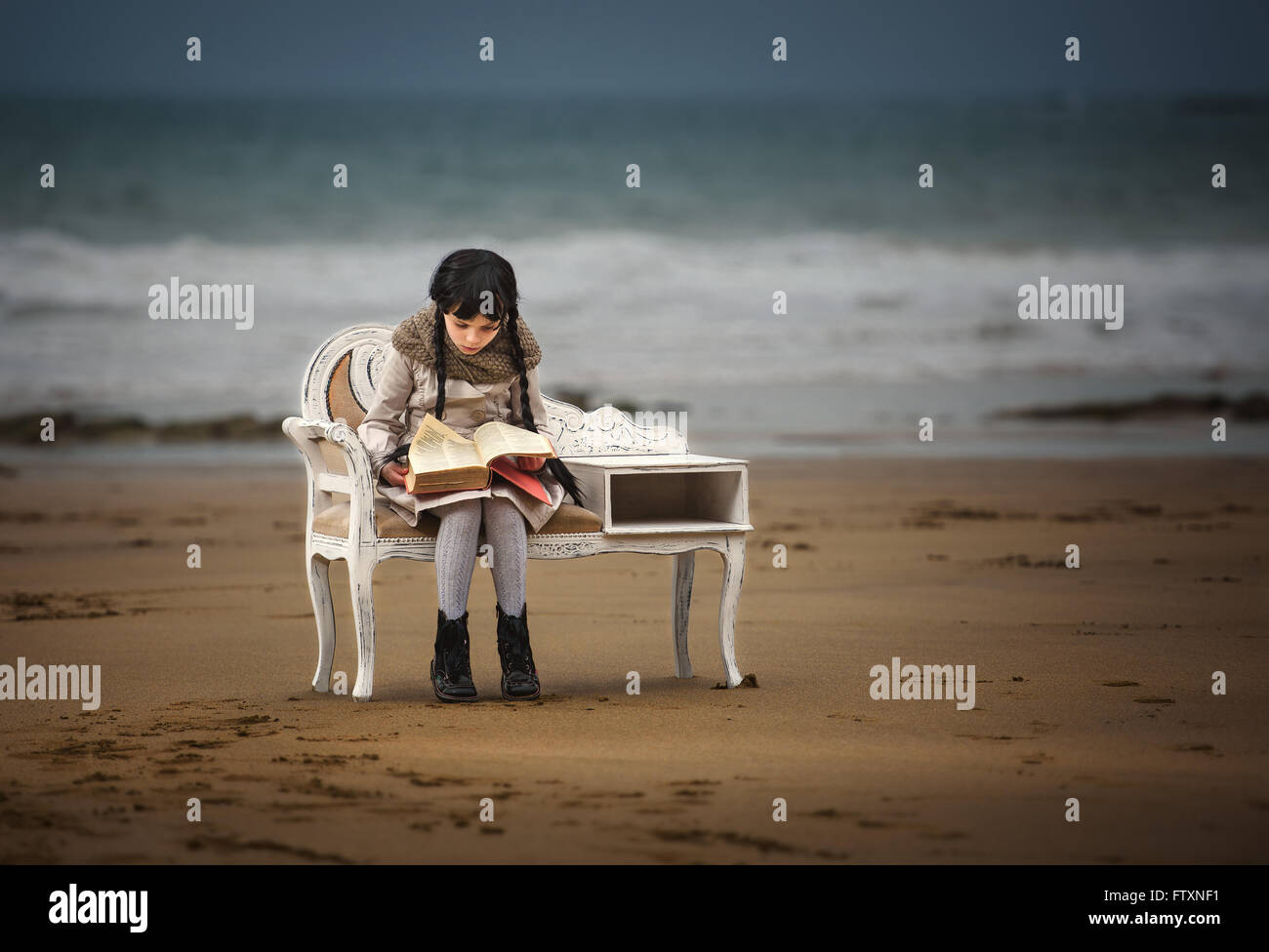 Mädchen lesen ein Buch am Strand Stockfoto
