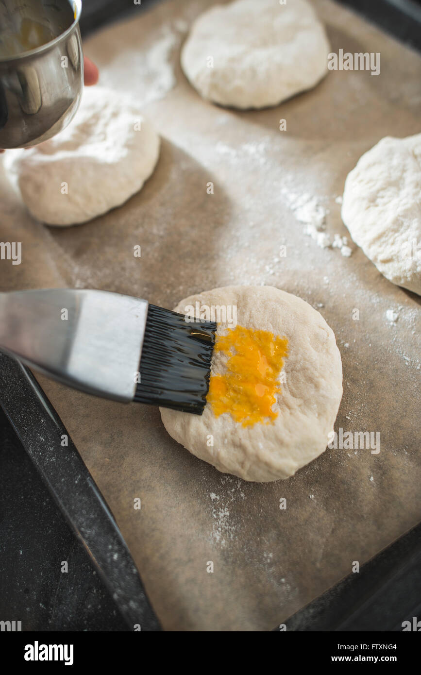 Junge Bürsten Brot Brötchen mit Ei zu waschen Stockfoto