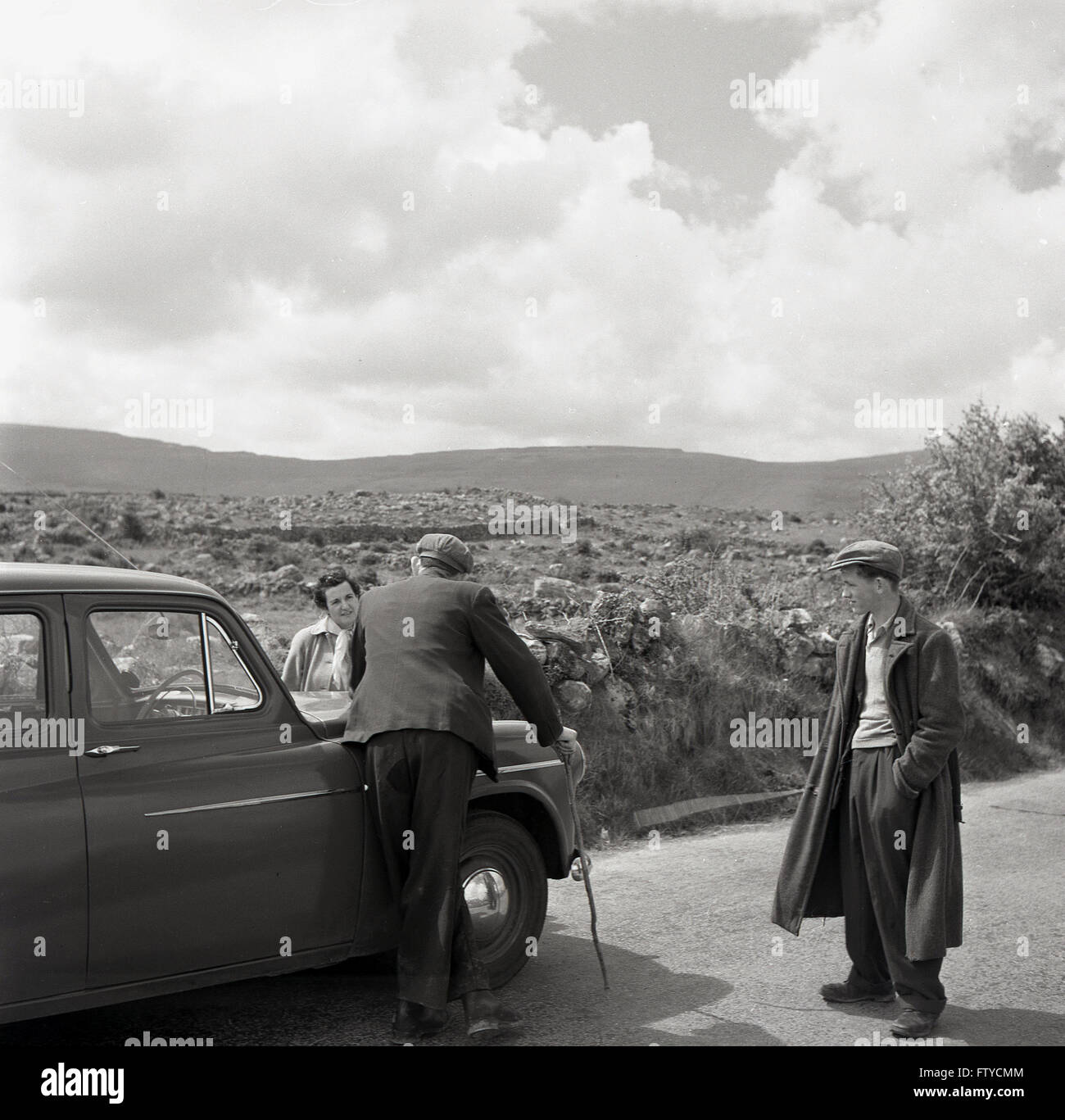 1950er Jahre historische, Betty Cash, Ehefrau des Fotografen J Allan Cash Chats an zwei Bauern oder Hirten auf einen Feldweg, westlich von Irland. Stockfoto