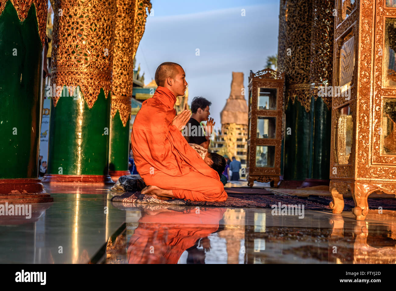 Asiatischer Mönch betet in der Shwedagon-Pagode bei Sonnenuntergang. Stockfoto