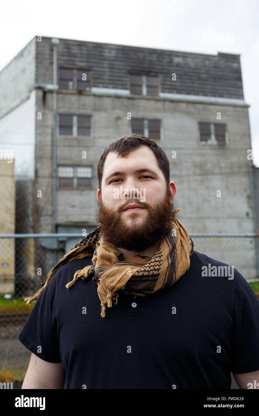Junger Erwachsener Mann im Freien in einem städtischen Umfeld für Lifestyle Portrait eines bärtigen Hipster. Stockfoto