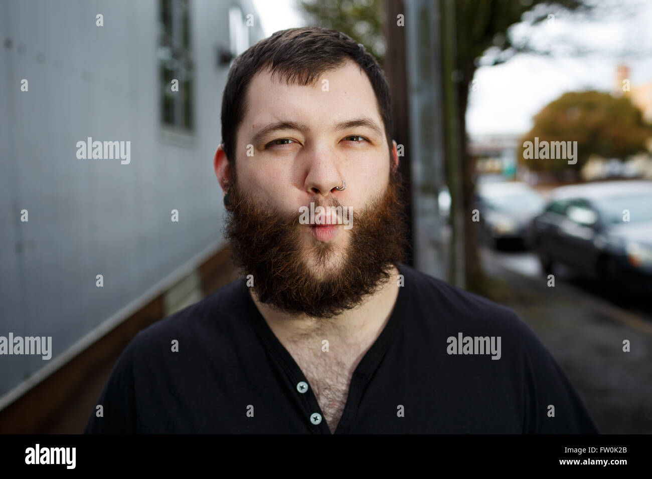 Junger Erwachsener Mann im Freien in einem städtischen Umfeld für Lifestyle Portrait eines bärtigen Hipster. Stockfoto