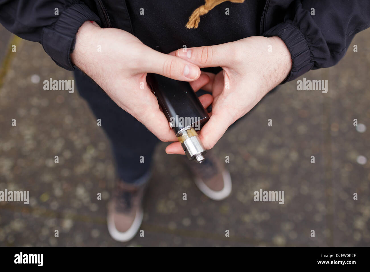 Urbaner Lifestyle Portrait von ein Mann Dampfen in einem städtischen Umfeld mit einem benutzerdefinierten Vape mod Gerät. Stockfoto