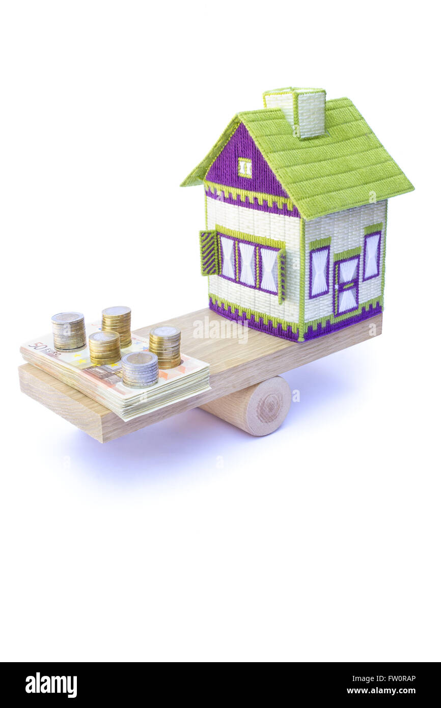 Wenig bestickte Haus per Saldo mit Haufen von Euromünzen und Banknoten, die isoliert auf weißem Hintergrund Stockfoto
