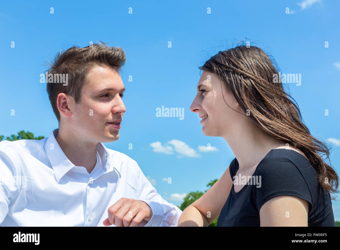 Junger Mann und Frau in Liebe sprechen im Freien mit blauem Himmel Stockfoto