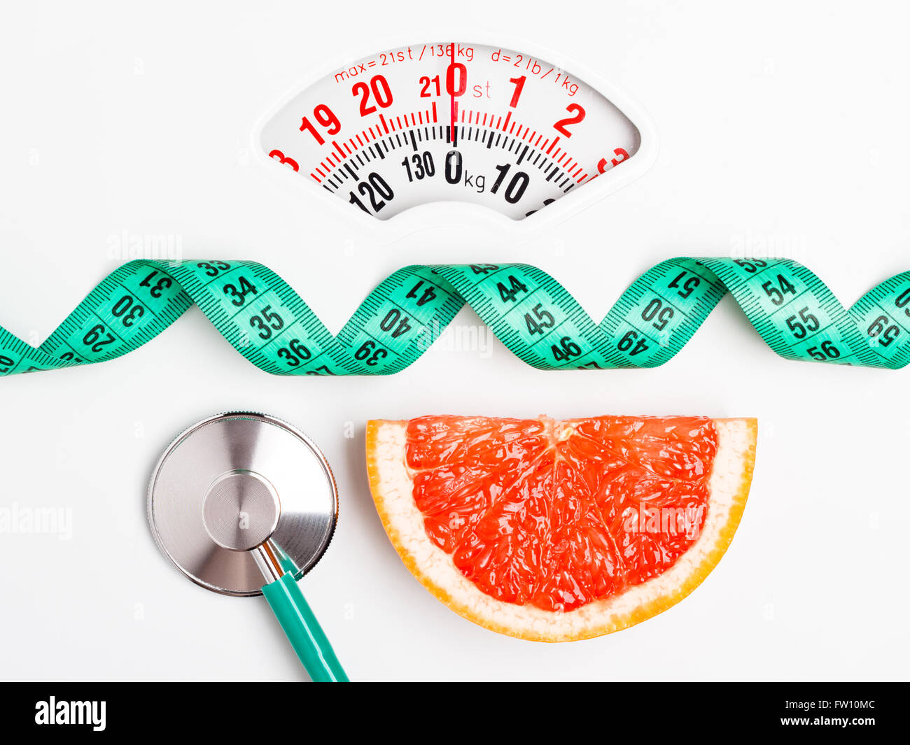 Ernährung gesunde Ernährung Gewicht Steuerungskonzept. Grapefruit mit Messung der Band und Stethoskop auf weißen Schuppen Stockfoto