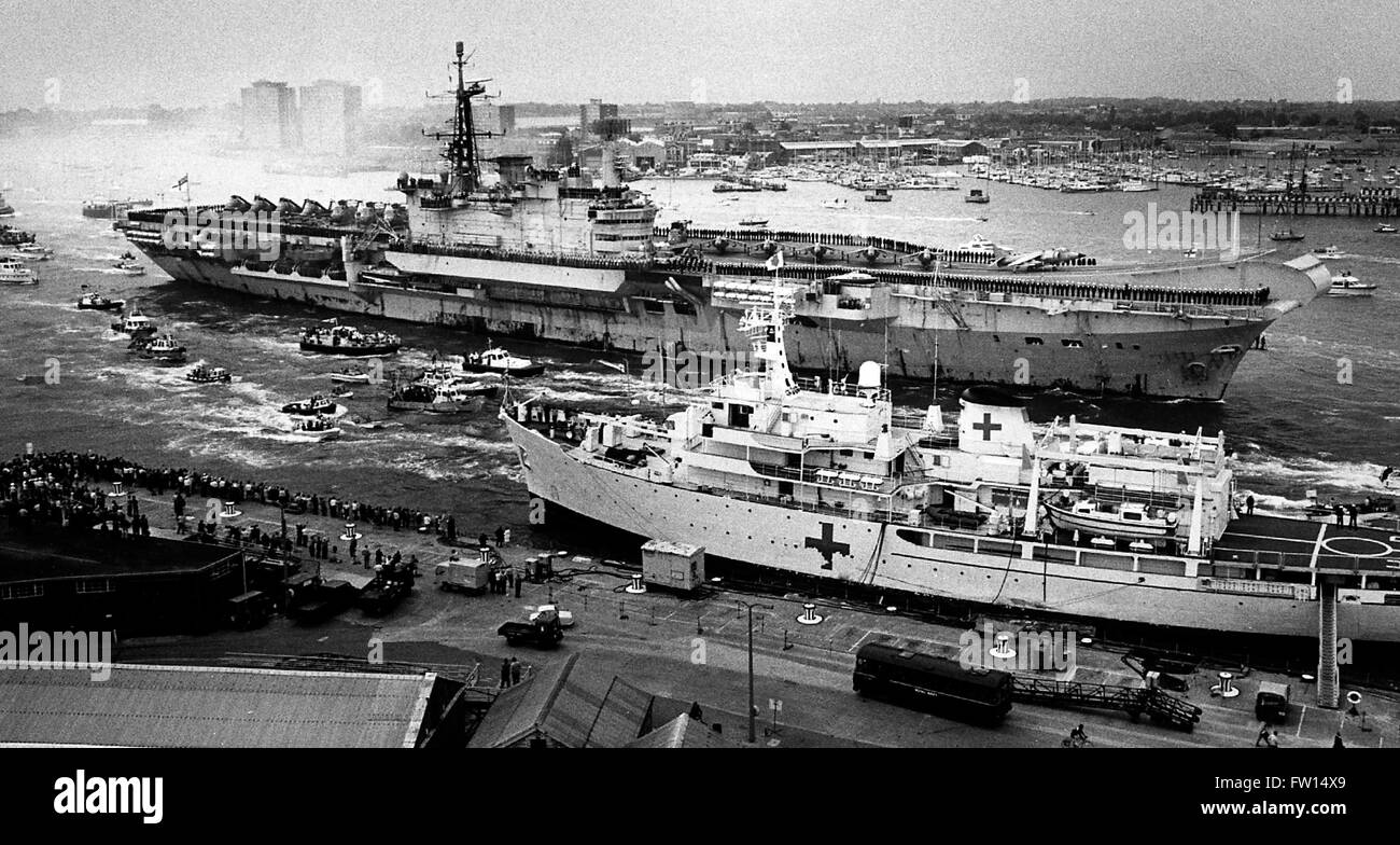 AJAXNETPHOTO. 21ST. JULI 1982. PORTSMOUTH, ENGLAND. - DER FRACHTFÜHRER KEHRT ZURÜCK - EIN ROST DURCHSTREIFTE HMS HERMES, IHRE CREW AN IHREN DECKS, KEHRT AM ENDE DES SÜDATLANTISCHEN FALKLANDINSELN-KRIEGES ZU IHRER HEIMATBASIS ZURÜCK, BEGLEITET VON EINER FLOTTILLE KLEINER BOOTE, DIE MIT WASSERFÄNGERN EINSCHIFFT WURDEN. IM VORDERGRUND STEHT DIE HMS HECLA, EINES VON MEHREREN UNTERSUCHUNGSSCHIFFEN, DIE WÄHREND DES KONFLIKTS ZU KRANKENHAUSSCHIFFEN UMGEBAUT WURDEN. FOTO: JONATHAN EASTLAND/AJAX REF:820721 3 Stockfoto