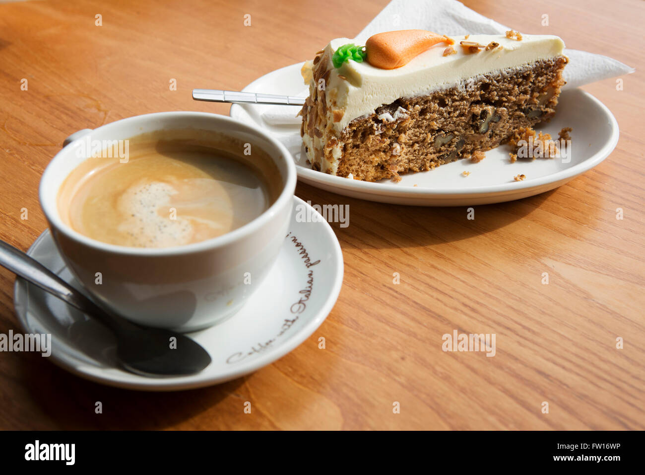 Eine Tasse Kaffee und ein Stück Karottenkuchen serviert in Edinburgh, Schottland. Gekrönt wird die Karotte-Kuchen mit Fondant. Stockfoto