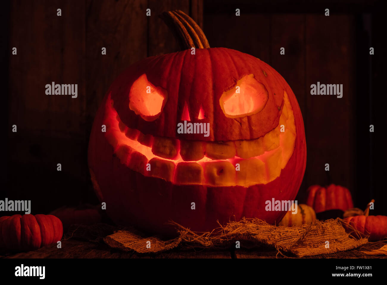 Glühende geschnitzte Kürbis oder Jack-o-Laterne für Halloween in rustikalem Ambiente mit Kerzen Stockfoto