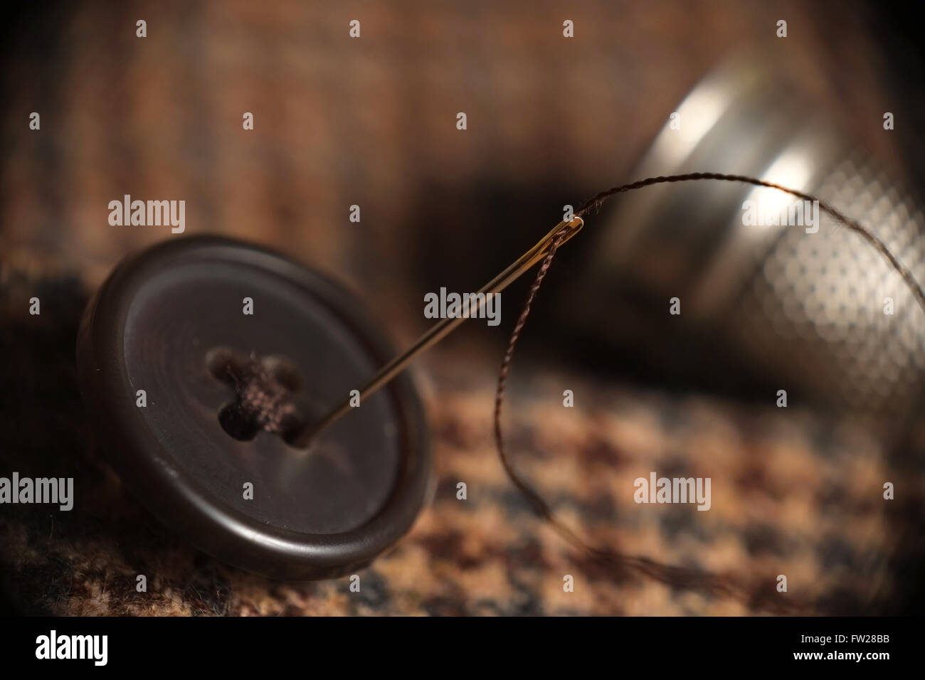 Makro von Nadel- und Taste auf einem Tweed Hintergrund Stockfoto Makro von Nadel- und Taste auf einem Tweed Hintergrund Stockfoto