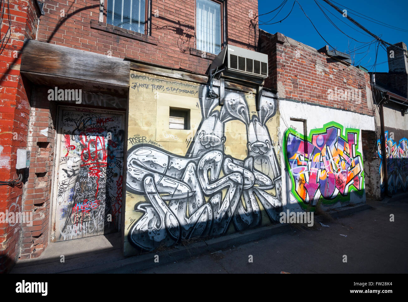 Ein Graffiti bedeckte Wand und Tür an einem Gebäude in einer Seitengasse der Kensington Market in Toronto Ontario Kanada. Stockfoto