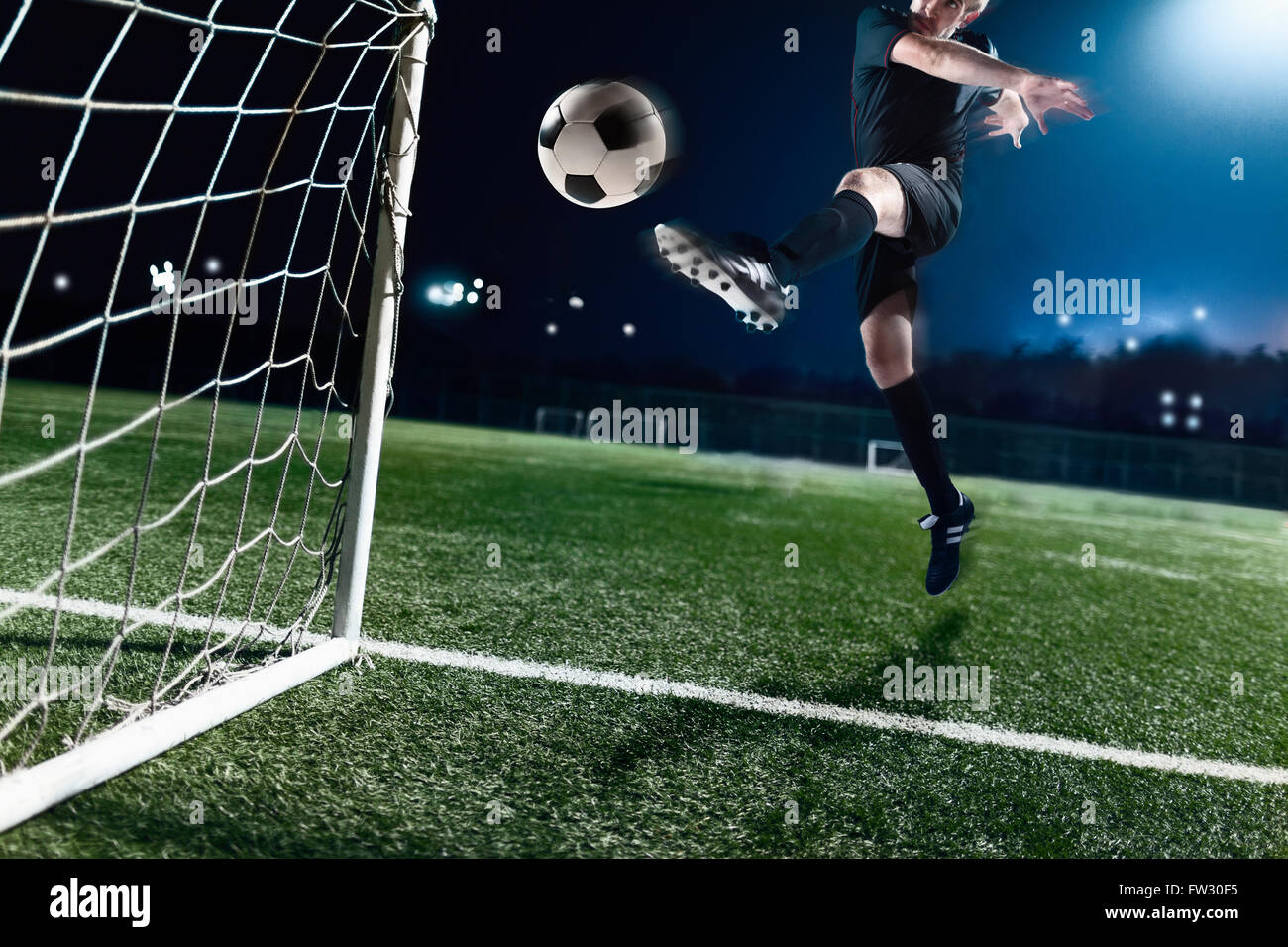 Athleten treten Fußball in ein Tor Stockfoto