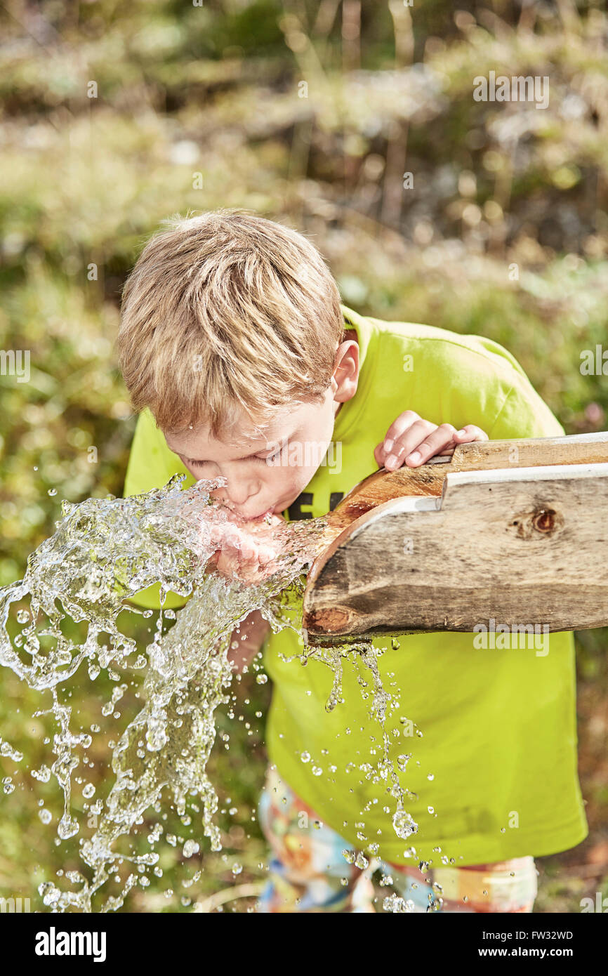 Blonder Junge Trinkwasser aus einem Brunnen, Hintertux, Zillertal, Tirol, Österreich Stockfoto