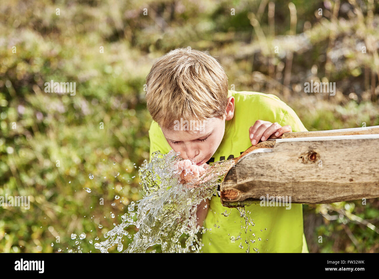 Blonder Junge Trinkwasser aus einem Brunnen, Hintertux, Zillertal, Tirol, Österreich Stockfoto