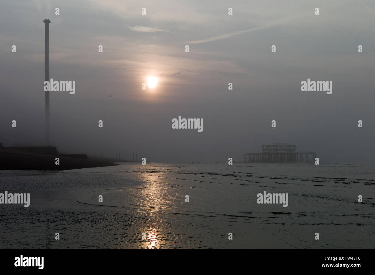 Sonnenaufgang am nebligen Morgen, Brighton Strandpromenade, mit verlassenen Pier West und i360 Aussichtsturm Stockfoto
