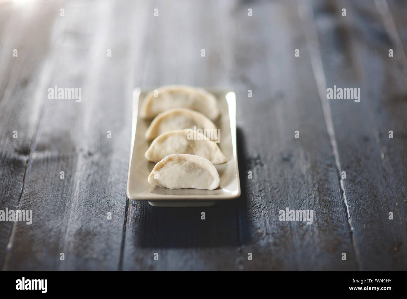 Hausgemachten Chinesischen Potstickers auf einem weißen Teller und blauem Hintergrund. Stockfoto