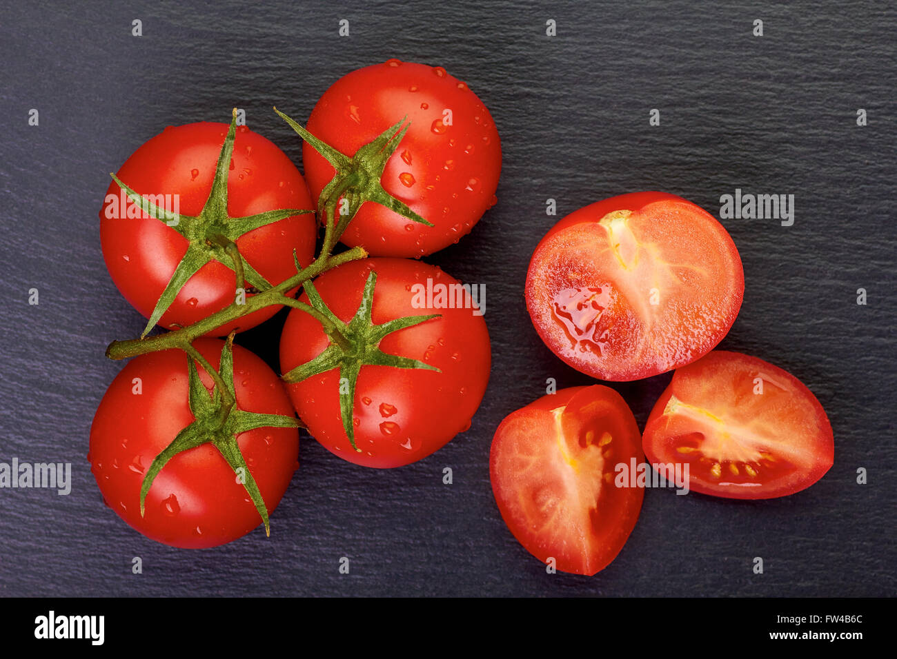 Reihe von Cherry-Tomaten mit Scheiben auf dunklen Stein Stockfoto