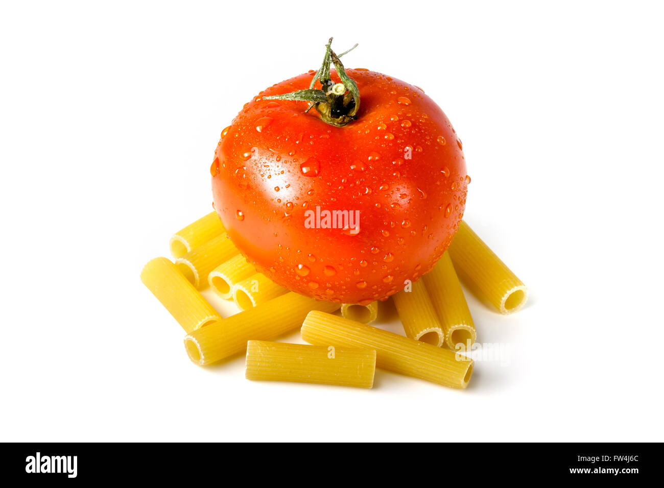 Frische Tomaten stehen auf rohe ungekochte Teigwaren isoliert auf weißem Hintergrund Stockfoto