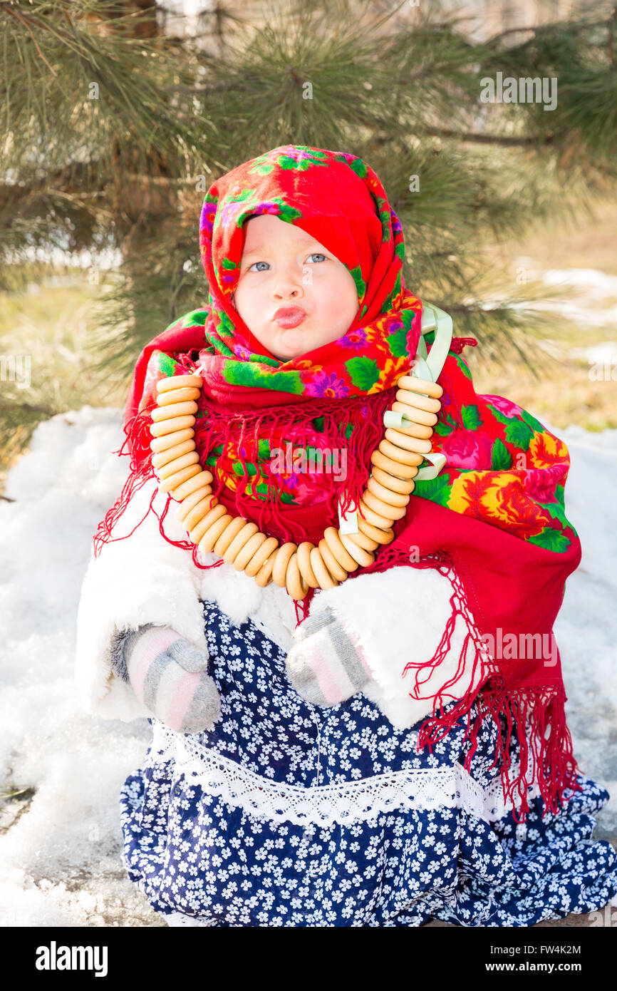 Kind Mädchen in russischen Pavloposadskie folk Schal auf Kopf mit  Blumendruck und Haufen von Bagels auf Grund von Schnee. Ill Stockfotografie  - Alamy
