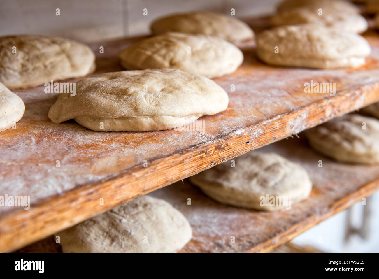 Rohen Brotteig geformt Brote auf Holzregalen bereit, in den Ofen in einer Bäckerei zu gehen bereit, Nahaufnahme Stockfoto