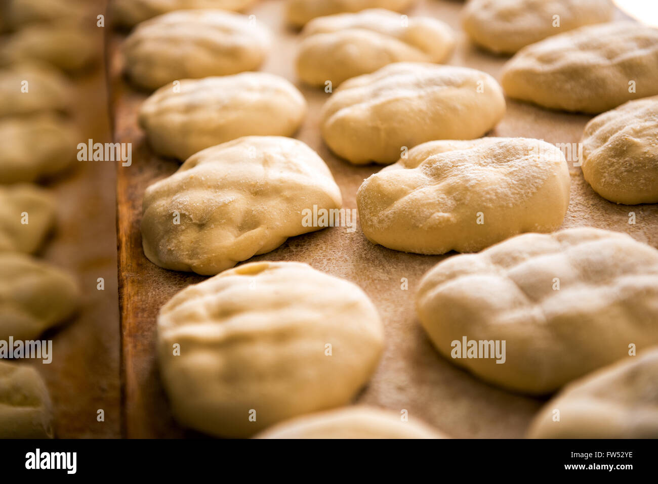 Frische Brote in einer Bäckerei mit zahlreichen rohen Teig-Portionen vorbereiten Stockfoto
