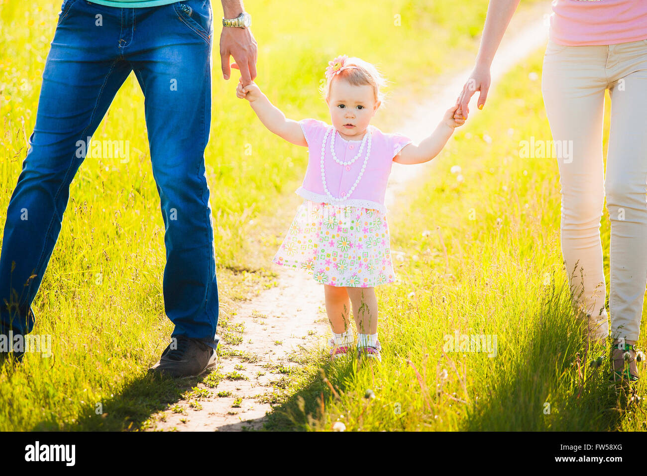 Kleine Tochter Hand in Hand von Mama und Papa. Porträt der glückliche Familie Stockfoto