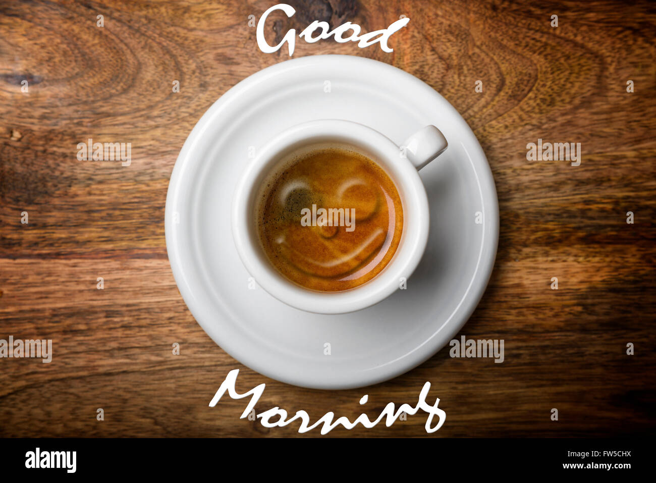 isolierte Kaffee Tasse oben anzeigen auf hölzernen Hintergrund mit guten Morgen geschrieben und Lächeln auf Kaffee-Schaum Stockfoto