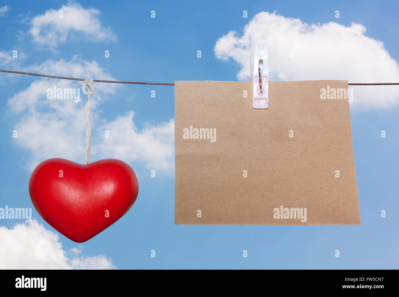 Braune Anmerkung Pad Wäscheklammer auf Drahtgewebe und Keramik Herz rot mit blauem Himmelshintergrund Stockfoto