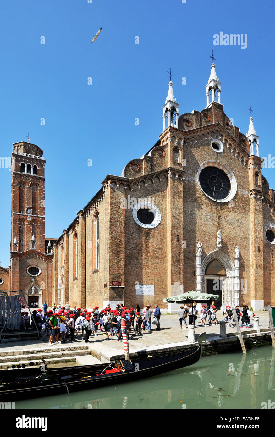 Frari-Kirche, auf dem Campo dei Frari, Bezirk San Polo, Venedig (mit Schulparty in roten Kappen). Die Basilica di Santa Maria Gloriosa dei Frari. Die Kirche ist die Himmelfahrt geweiht; Das Gebäude wurde in dem Jahrhundert nach 1338 abgeschlossen. Der Campanile, der zweite höchste in der Stadt, wurde 1396 fertiggestellt. Die Kirche enthält die Gräber von Tizian (Tiziano Vecelli oder Tiziano Vecellio), Canova und mehrere Dogen. Stockfoto