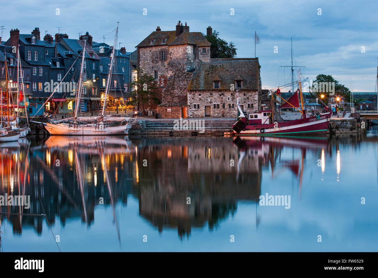 Häuser und Boote am alten Hafen mit Reflexion in ruhigem Wasser am Abend Vieux Bassin, Honfleur, Calvados, Normandie Stockfoto