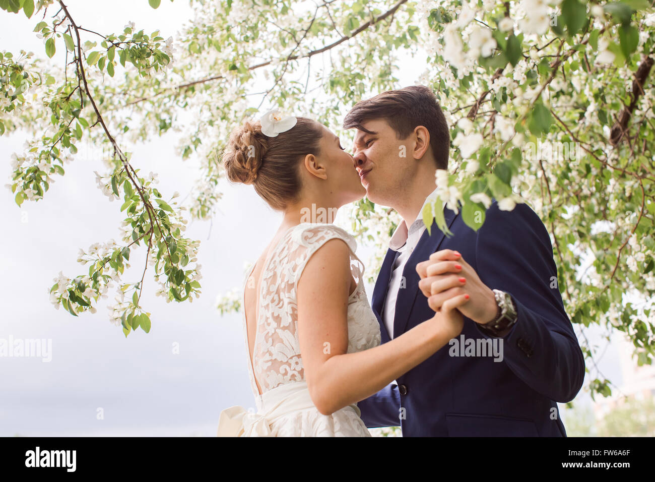 elegante stilvolle Bräutigam mit seiner glücklich wunderschöne Brünette Braut auf dem Hintergrund der Apfelblüte Bäume im park Stockfoto