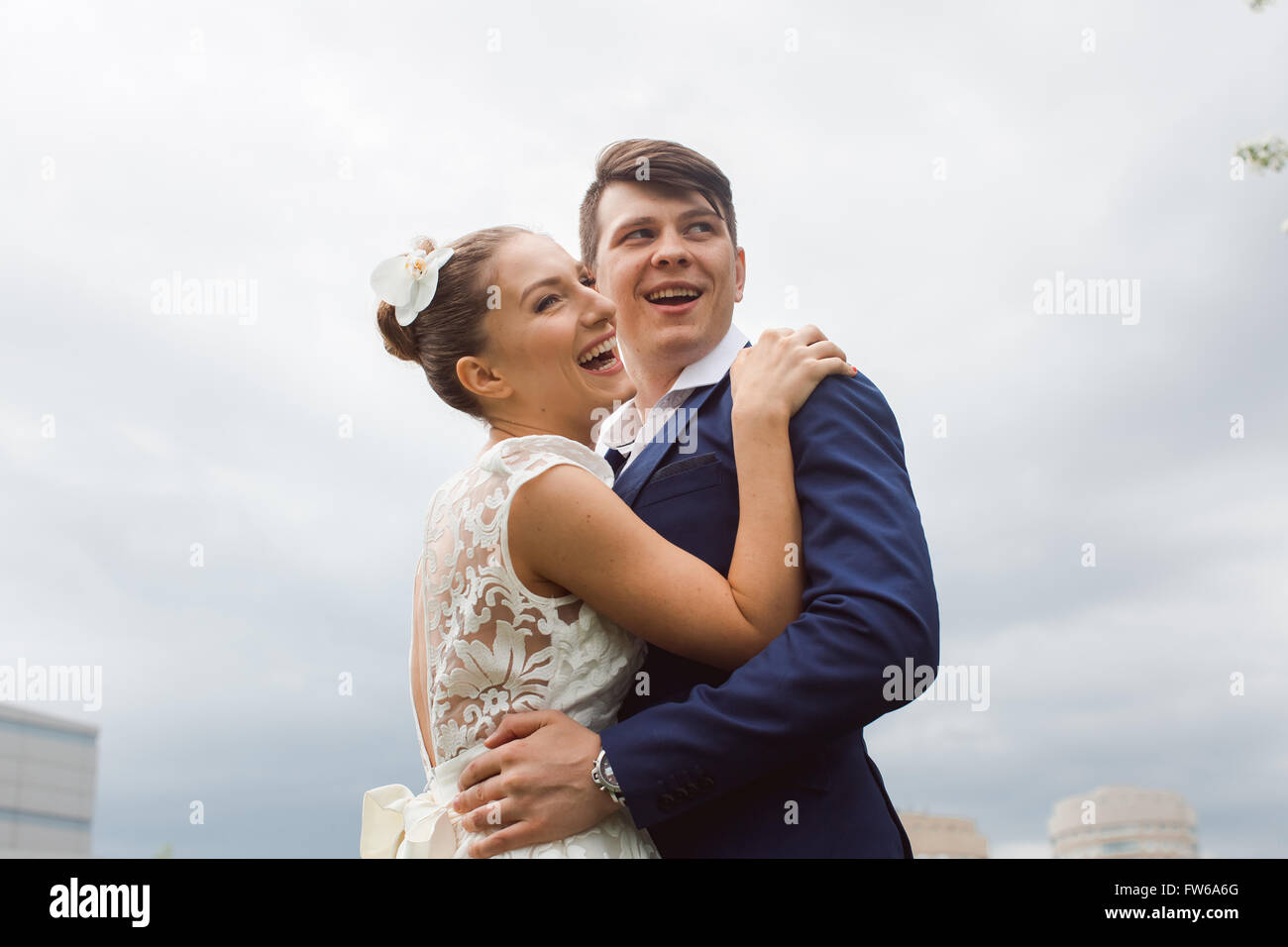 Porträt des jungen glücklich schöne Brautpaar umarmt und lachend auf blauen Himmelshintergrund Stockfoto