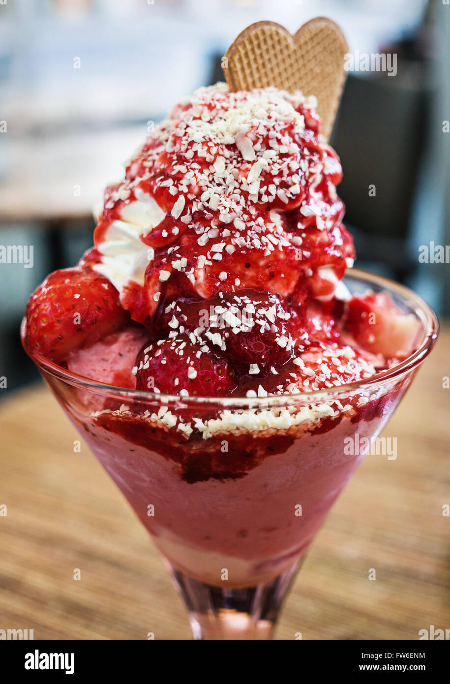 Eis-Dessert mit Erdbeeren und Schlagsahne serviert in einer Glastasse Stockfoto