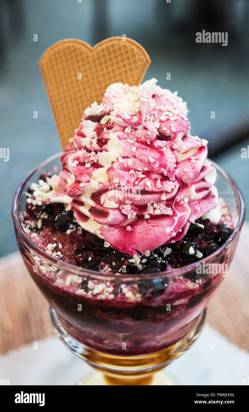 Eis-Dessert mit Beeren und Sahne serviert in einer Glastasse Stockfoto
