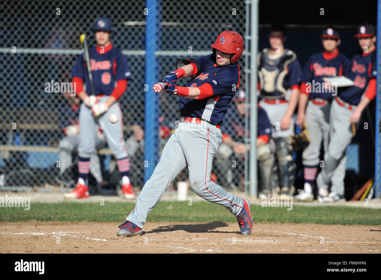 Linkshänder Teig erfolgreiche Kontakt während eines High School Baseball Spiel als seine Mannschaftskameraden vom Einbaum über beobachten. USA. Stockfoto