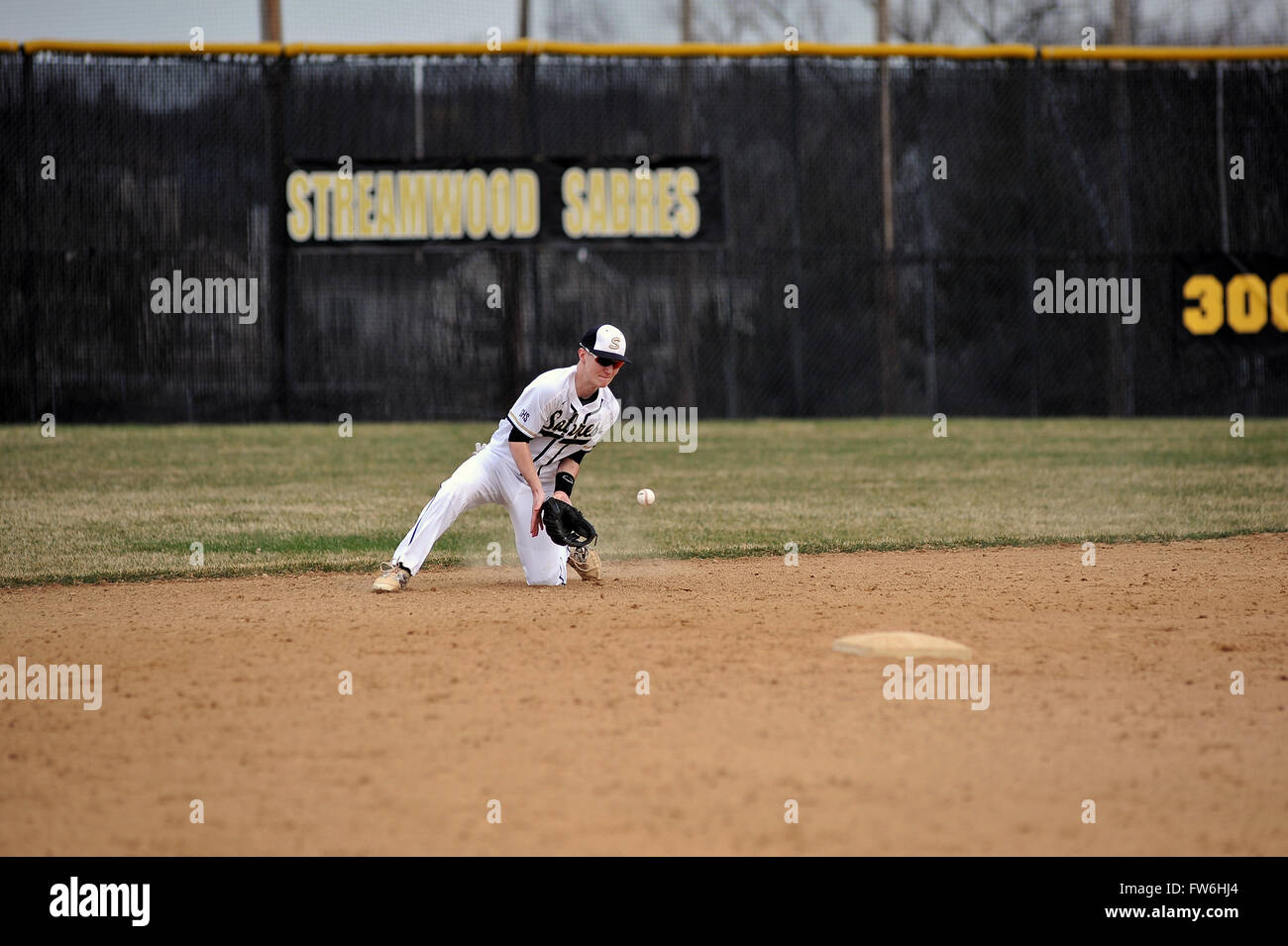 Zweiter Basisspieler hinunter in ein Knie in einer Bemühung, mit einem Ball hinter der zweiten während der High School Baseball Spiel zu beschäftigen. USA. Stockfoto