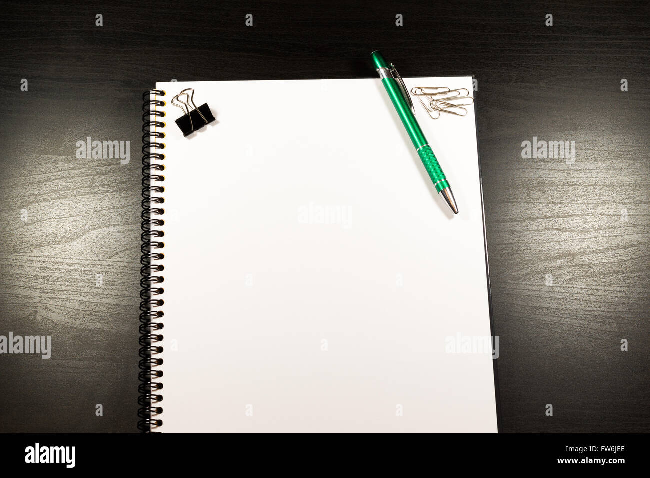 Notebook mit leerem Papier, Farbe, Haftnotizen, Stift und Clips auf einem Holztisch Stockfoto