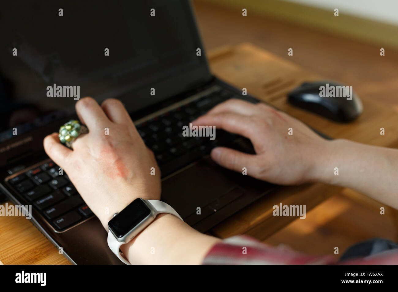 Händen der Trägerin Smartwatch auf der Tastatur ihres Notebook-PCs. Stockfoto