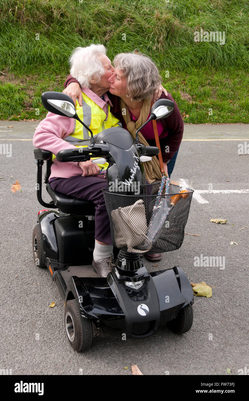 Ältere Frau sitzt in ihrem Elektromobil küssen und umarmen ihr aufhalten Stockfoto
