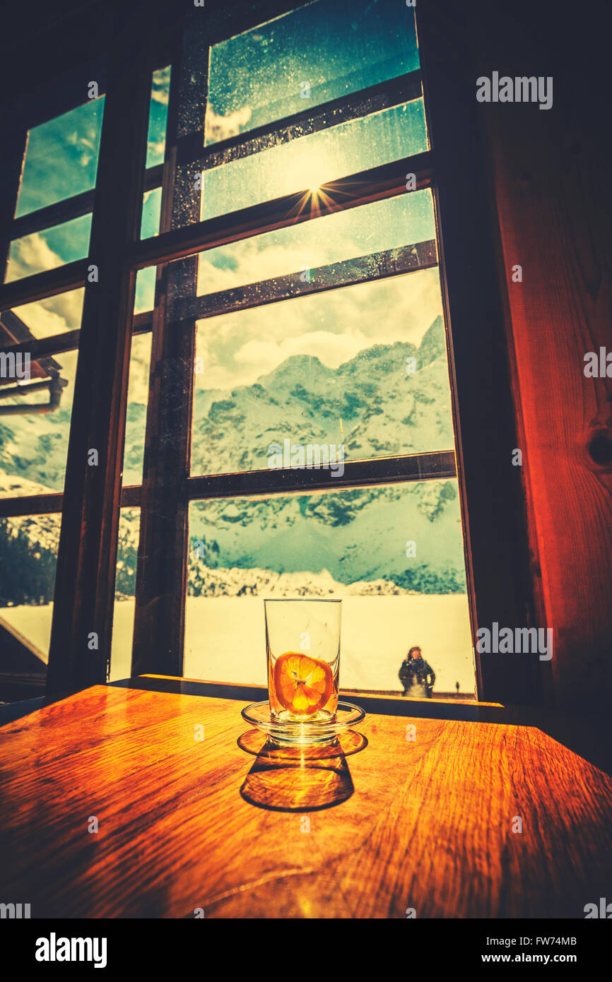 Retro-stilisierte leeres Teeglas mit gepressten Zitronenscheibe auf Holztisch mit Blick auf die Berge. Stockfoto