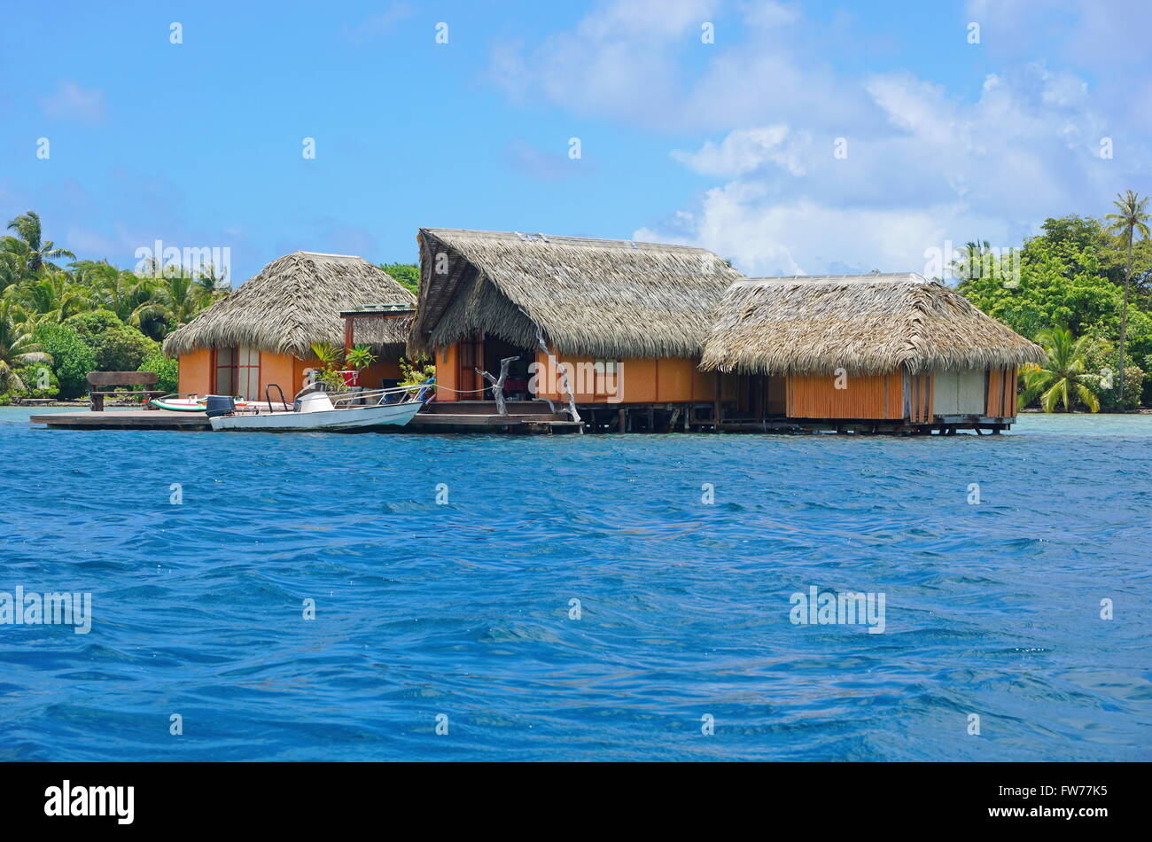 Tropischen Heimat über Wasser mit Strohdach und einem Boot im Dock, Huahine Insel, Pazifik, Französisch-Polynesien Stockfoto