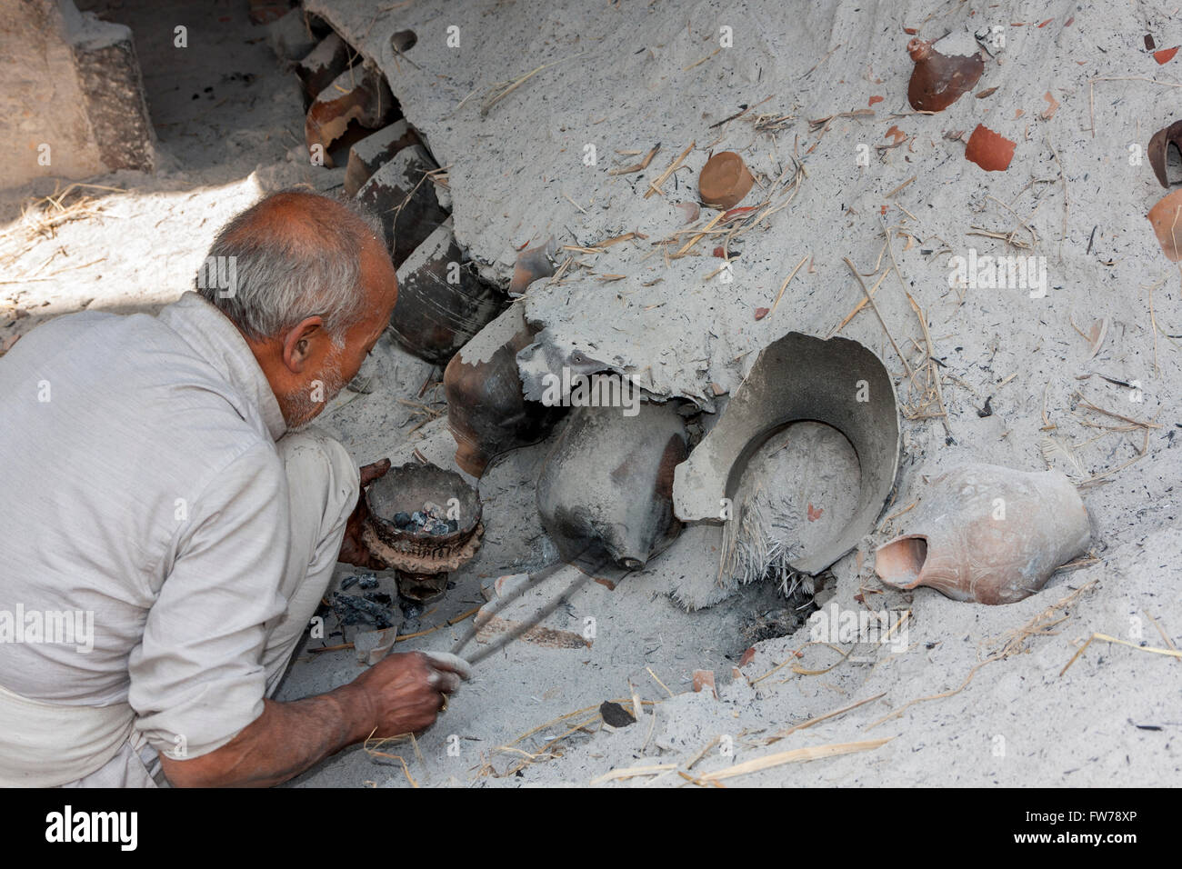 Bhaktapur, Nepal.  Potter an Arbeit dazu neigt seinen Brennofen in Potters' Square. Stockfoto