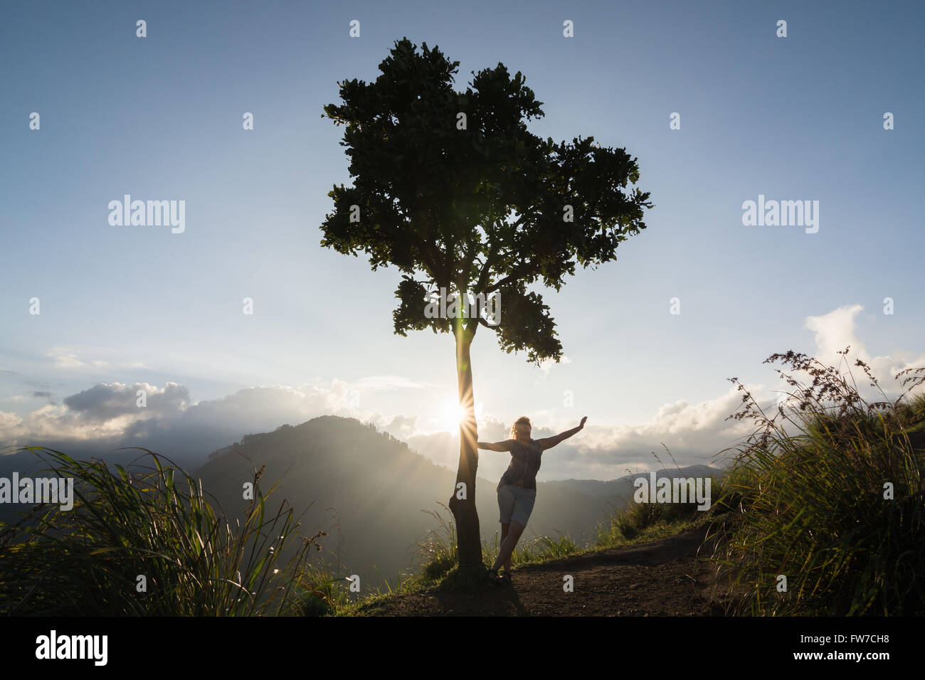 Hintergrundbeleuchtung Silhouette einer Frau und Baum auf dem Hügel Stockfoto