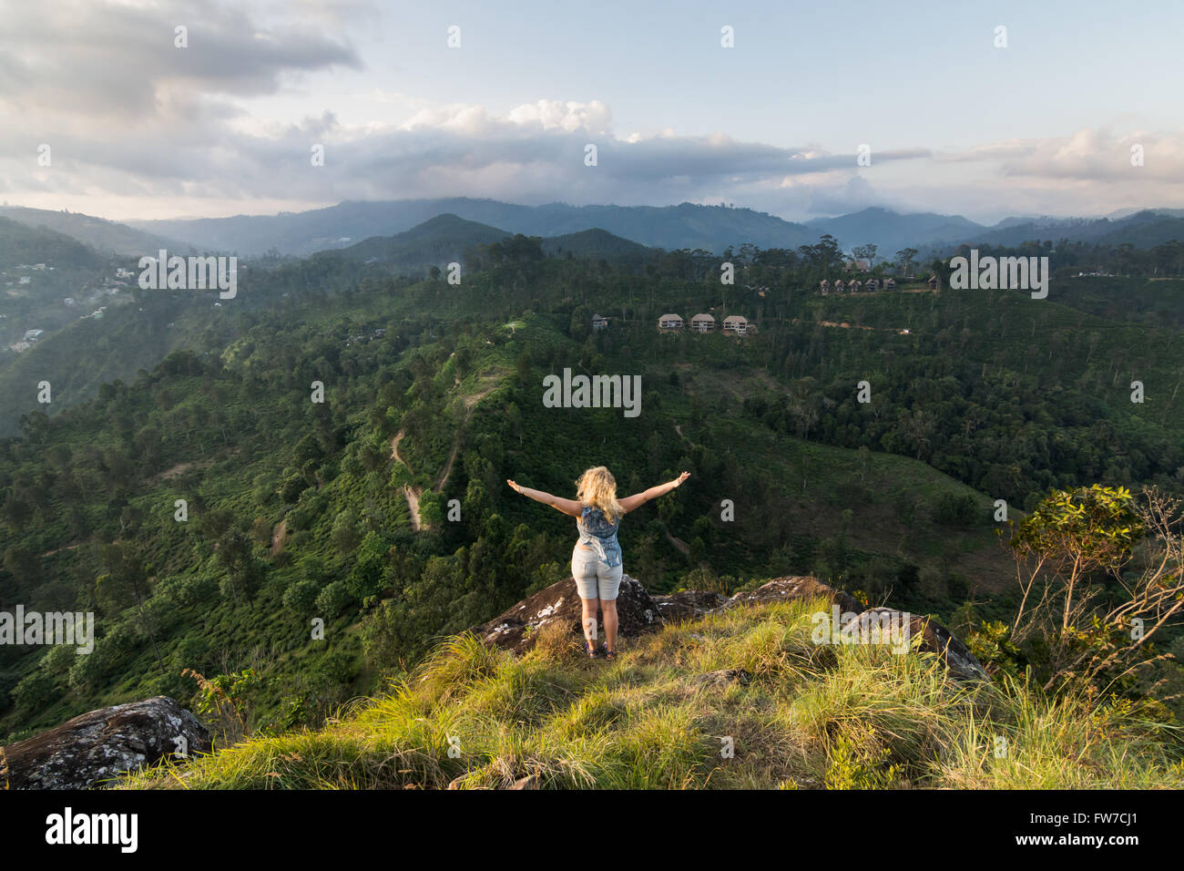 Frau steht am Rand eines Hügels Stockfoto