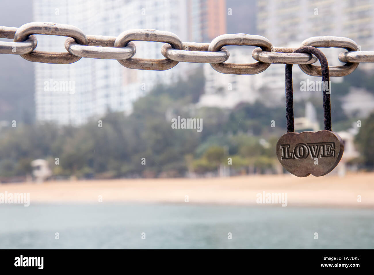 Vorhängeschloss mit Text Liebe hängt an einer Kette am Strand Stockfoto